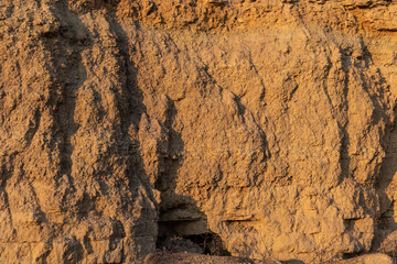 Cliff surface of yellow-orange color with a cave.  Texture for background.