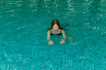 Portrait of beautiful woman in swimwear relaxing in swimming pool spa.