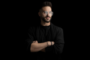 happy bearded man wearing glasses, looking to side and crossing arms