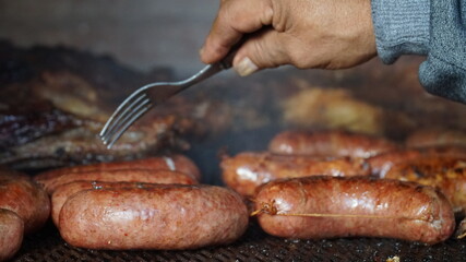 Chorizos a punto de ser pinchados en un asado argentino.  