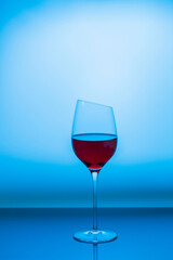 Close up view of red wine being poured into graceful slim wine glass isolated on blue background. Sweden.