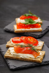 Small snacks of slices, curd cheese, red fish, tomatoes and caviar. On stone