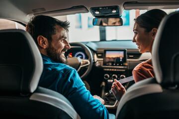 Beautiful young couple at car showroom choosing a new car to buy.