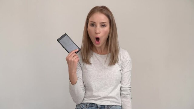 Disturbed girl with ginger hair has problematic concerned face expression, holding smartphone, jealous and sorting out the relationship with somebody