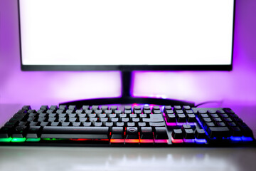 Gamer computer monitor with LED lights on at night and colorful backlit keyboard.