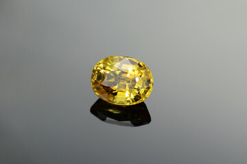 Genuine yellow sapphire gemstone. Beryllium treated, heated, color enhanced, oval faceted shaped, loose transparent precious stone setting from Sri-Lanka. Slight inclusions. Gradien background. 