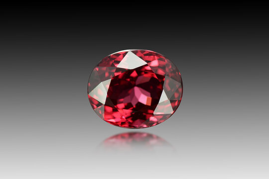 Genuine cherry red color spinel faceted gemstone. High quality finish sample. Deep saturated, flawless, oval faceted transparent loose natural stone setting. Gray gradien background. Blure reflection.