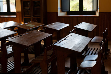 Pupitres antiguos de madera con huecos para tintero de los años 40 en una antigua aula escolar.