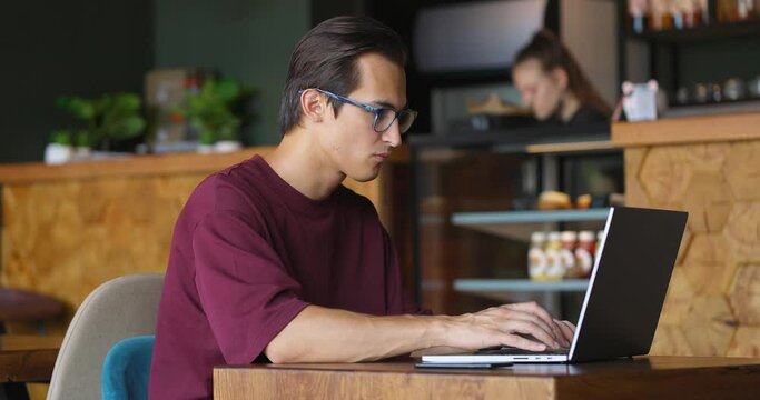 Side view shot of a freelancer typing on laptop keyboard in cafe