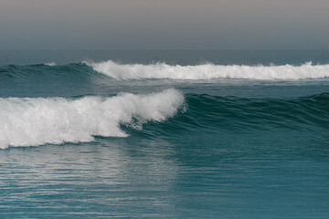 wave breaking on the beach - blue ocean with two parallel waves