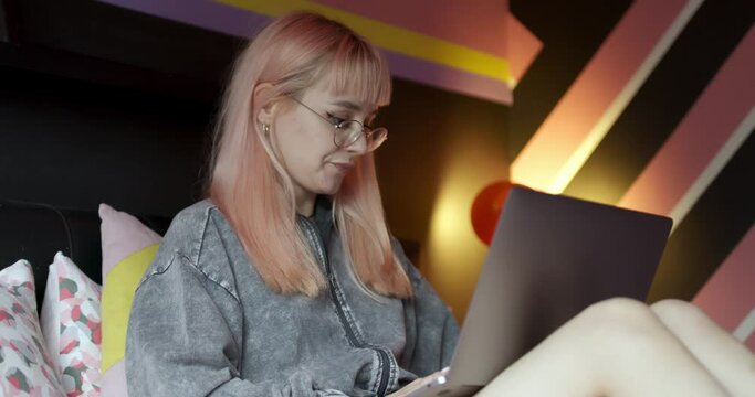 Young adult gen z female student using a laptop in her bedroom
