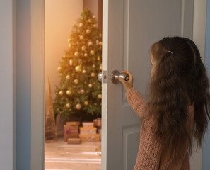 Little girl opening door to room decorated for Christmas
