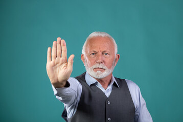 Old man showing stop sign with palm in studio