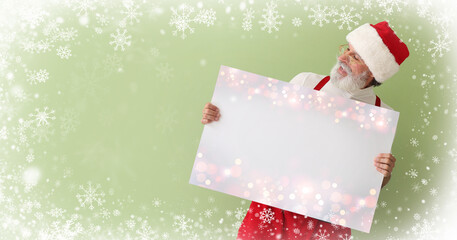 Santa Claus with blank poster on green background