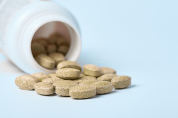 Fototapeta na wymiar Daily vitamins on a light background. Light brown pills