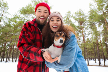Happy young couple with dog in forest on winter day