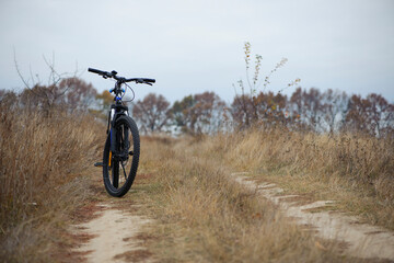 bike stands on in the field. A mountain bike stands on a field path with dry autumn grass. cycling....