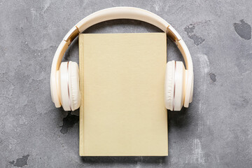 Modern headphones and book on grey background
