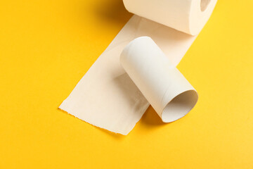 Roll of toilet paper and empty cardboard tube on yellow background, closeup