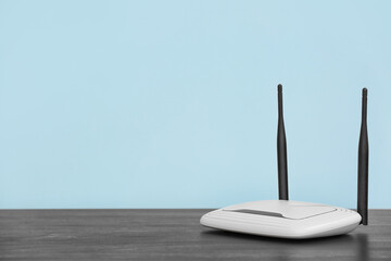 Modern wi-fi router on table near blue wall