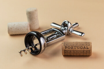 Corkscrew with corks on beige background. Name of wine country Portugal is written on the cork.