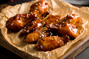 chicken wings in teriyaki sauce on the board side view on brown concrete table macro close up