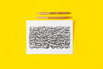 Paper with Arabic text and dip pens on color background