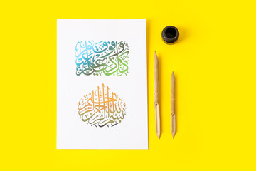 Paper with Arabic text and tools for calligraphy on color background
