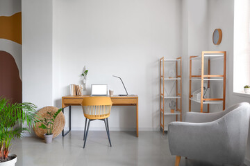 Interior of room with comfortable workspace, shelves and armchair