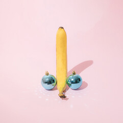 Yellow banana with two light blue party disco ball on pink pastel background. Minimal holiday design.