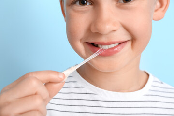 Little boy with chewing gum on blue background, closeup