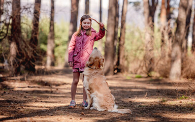 Little girl with golden retriever dog in the wood