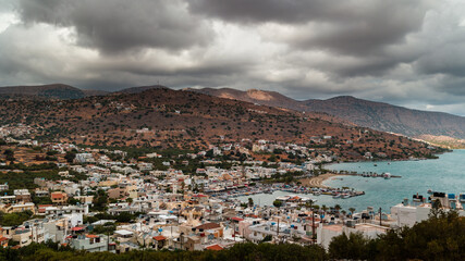Fototapeta na wymiar Stormy clouds and bands of rain over the Greek tourist resort town of Elounda on the island of Crete