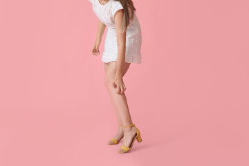 Young woman scratching herself on color background