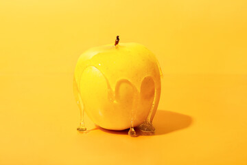 Sweet honey flowing down from ripe apple on color background