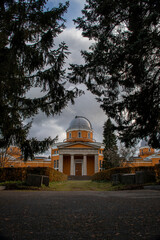 orange observatory building behind spruce trees in park