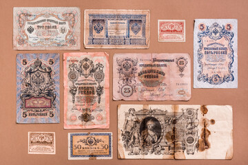 Old worn out of circulation ruble banknotes of royal russia on a brown background. Knolling top view