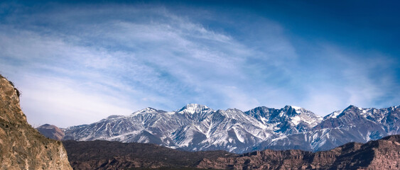 Snowy Andes mountains and wispy clouds, seen from Potrerillos, Mendoza, Argentina, in a sunny,...