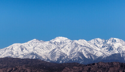 Snowy Andes mountains, as seen from Potrerillos, Mendoza, Argentina, in a sunny, bright winter day. - obrazy, fototapety, plakaty
