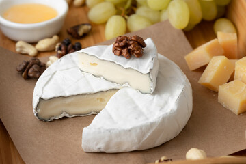 Brie cheese with nuts and grapes on a wooden tray