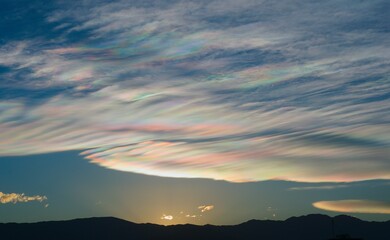 Thin wispy clouds creating rainbow patterns of scattered sunlight. Optical phenomenon on...