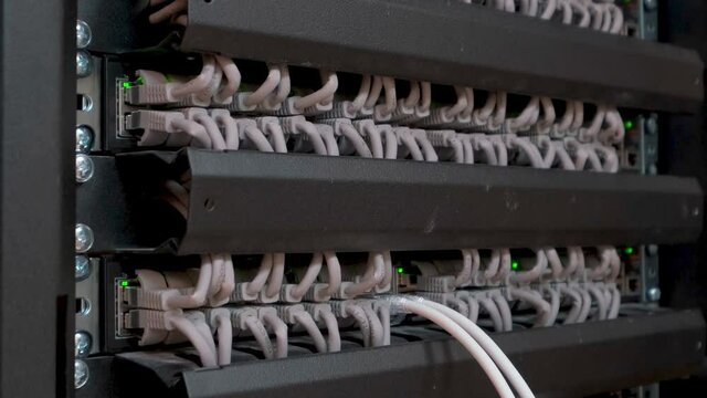 large number of wires and cables in modern server and network equipment with flashing green lights and optical severs computer in rack at data center