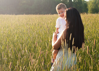 Mother holds her son in her arms and hugs. Happy family and parental love concept
