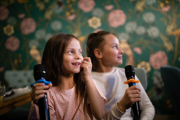 Two girls singing with microphones in karaoke club