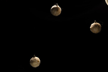 three christmas balls suspended on a black background