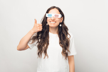 Cheerful wide smiling woman is showing thumb up while wearing a pair of 3D glasses.