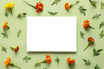 Blank sheet of paper and marigold flowers on color background, closeup