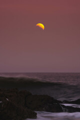 First glare of the moon over the splashing sea water at sunset