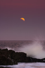 First glare of the moon over the splashing sea water at sunset