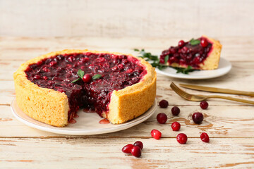 Plate with tasty lingonberry pie on light wooden table